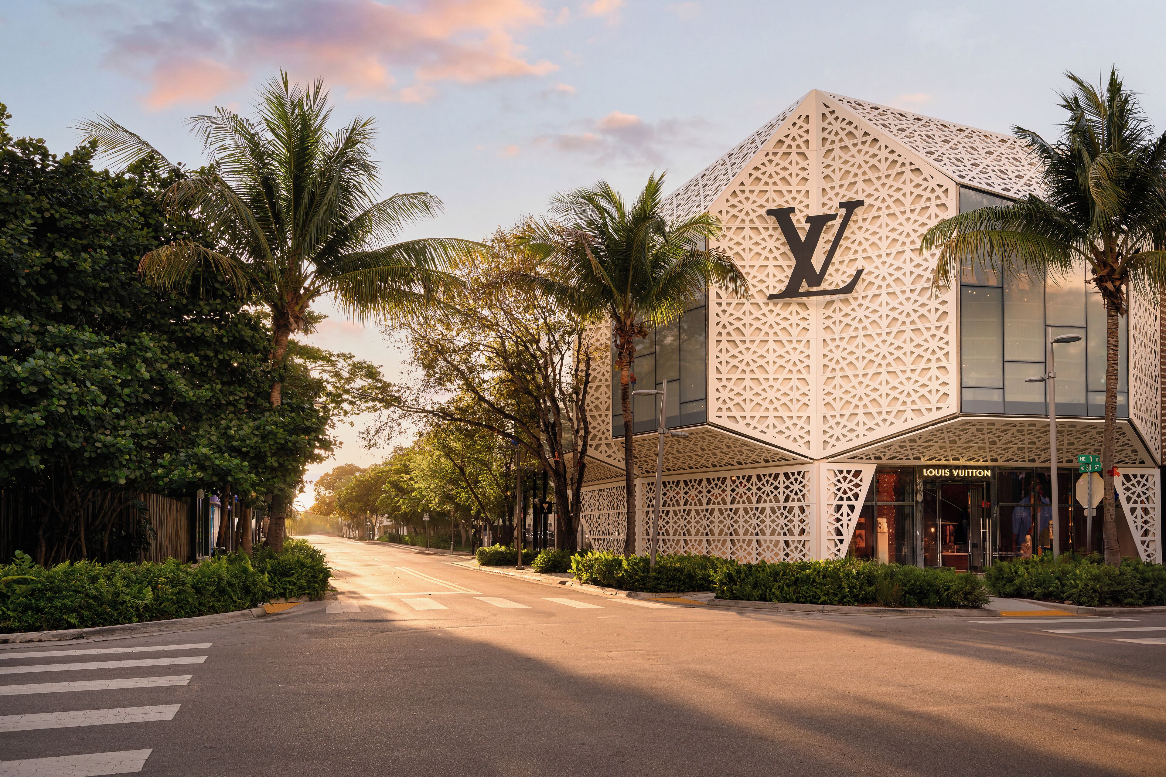 A Louis Vuitton store with a distinctive geometric facade, palm trees, and a crosswalk.