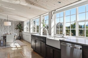 Une cuisine moderne avec de grandes fenêtres, un coin repas et une plante.