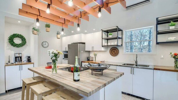 A modern kitchen with a central island, pendant lighting, and a view of the outdoors. - Barndo2 Modern European Style Home of Fluffy Cows (Jefferson City)