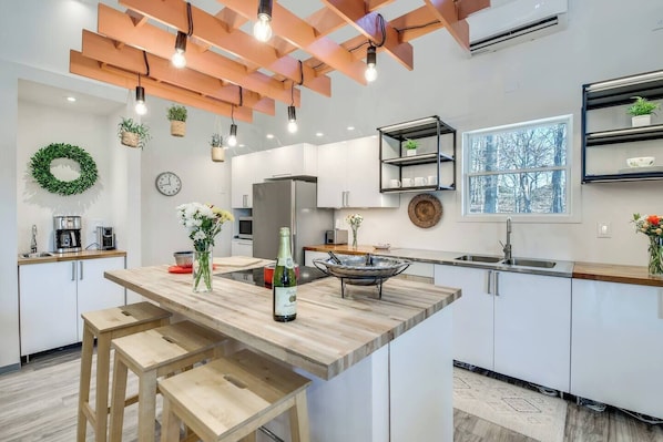 A modern kitchen with a central island, pendant lighting, and a view of the outdoors.