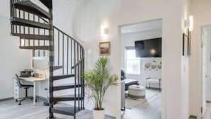 A modern interior with a spiral staircase, a desk with a typewriter, a potted plant, and a living area with a sofa and ottoman. - Barndo2 Modern European Style Home of Fluffy Cows (Jefferson City)