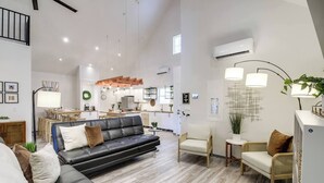 A spacious living area with a black leather sofa, a wooden dining table, and a kitchen in the background. - Barndo2 Modern European Style Home of Fluffy Cows (Jefferson City)