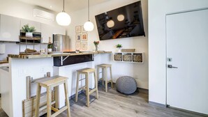 A modern kitchen with wooden stools, a TV mounted on the wall, and a white door. - Barndo2 Modern European Style Home of Fluffy Cows (Jefferson City)