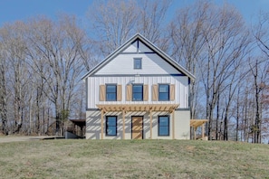 A two-story house with a front porch, a garage, and a view of a lake.