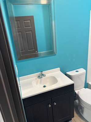 Een badkamer met een wastafel, spiegel, toilet en kastjes.