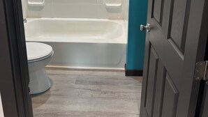 Ein Badezimmer mit Badewanne, Toilette und einer Tür.