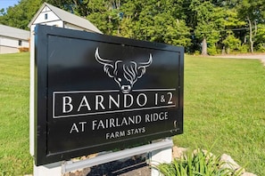 Een bord met 'Barndo 1&2 bij Fairland Ridge Farm Stays', met een logo van een stier.