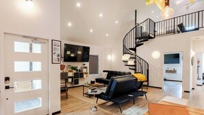 Una sala de estar moderna con un sofá negro, una mesa de centro y una escalera.