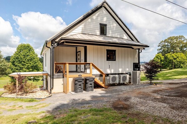 A single-story building with a porch, a staircase, and a small outdoor seating area. - Barndo1 Fluffy Cow Farm Stay at Cedar Pond Farms (Jefferson City)