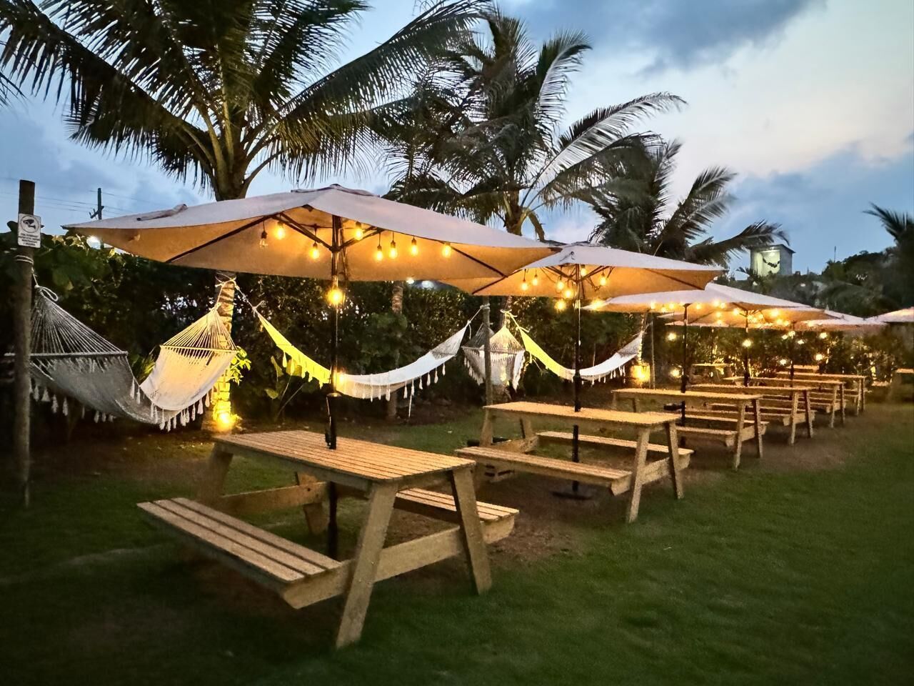 Outdoor seating with tables and hammocks, under string lights.