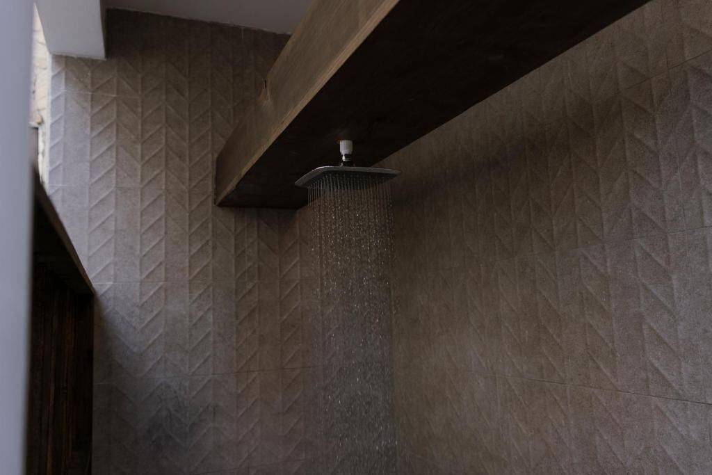 Une douche au design moderne, un mur à texture et une structure en poutres apparentes.