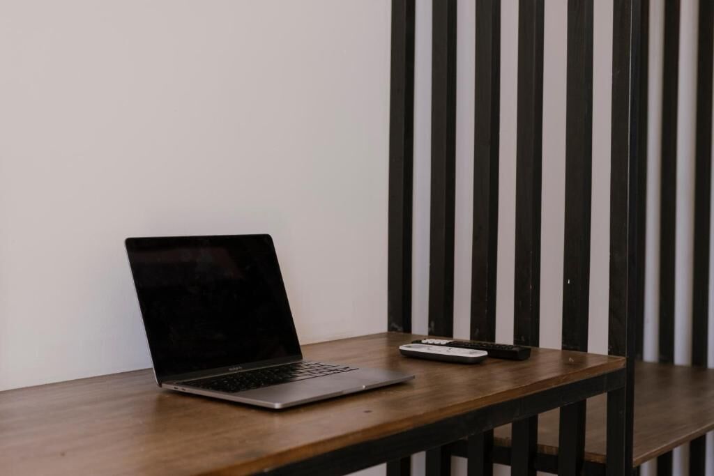 Ein Laptop auf einem Holztisch vor einem schwarz-weiß gestreiften Hintergrund.