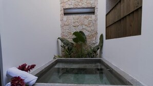 A spa area with a stone wall, a small window, and a glass-enclosed hot tub.