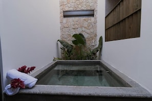 A spa area with a stone wall, a small window, and a glass-enclosed hot tub.