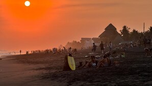 A beach scene with people, a pyramid structure, and a sunset.