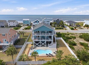 A beachfront property with a large pool, multiple balconies, and ocean views.