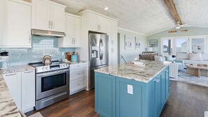 Una cocina con armarios blancos, un refrigerador de acero inoxidable y una isla azul.