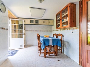Ein Essbereich mit Tisch für vier Personen, Holzsesseln, einer Vitrine und einer Tür zu einem anderen Raum.