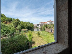 Ein Fluss mit Häusern an einem Hügel, betrachtet durch ein Fenster.