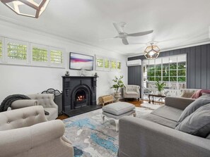 Ein Wohnzimmer mit Kamin, Deckenventilator und Blick ins Freie.