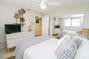 A bedroom with a bed, a TV, a dresser, a mirror, and a ceiling fan. - Amazing 4th floor 3/2 condo at Sand Dollar Unit 3-407! (St. Augustine)