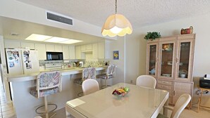 Cocina compacta con isla central, mesa de comedor y sillas.