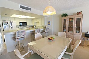 A compact kitchen with a central island, dining table, and chairs. - Incredible Direct Oceanfront Views from 6th Floor Balcony at Sand Dollar 3-604 (St. Augustine)