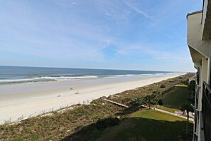 A beach view from a balcony overlooking a sandy beach with a clear sky. - Incredible Direct Oceanfront Views from 6th Floor Balcony at Sand Dollar 3-604 (St. Augustine)