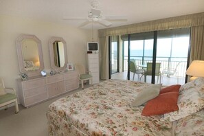 A hotel room with a bed, a dresser, a TV, a chair, and a balcony with a view. - Incredible Direct Oceanfront Views from 6th Floor Balcony at Sand Dollar 3-604 (St. Augustine)