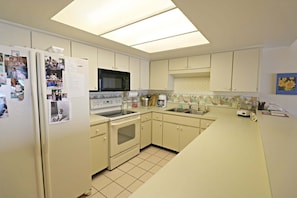 A compact kitchen with a refrigerator, microwave, oven, and sink. - Incredible Direct Oceanfront Views from 6th Floor Balcony at Sand Dollar 3-604 (St. Augustine)