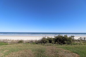 Blick auf einen Strand mit einem hölzernen Steg, der zum Ufer führt.
