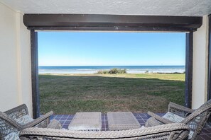 Eine Terrasse mit Korbmöbeln und Blick auf den Strand.