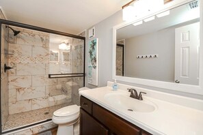 Ein Badezimmer mit Dusche, Toilette, Waschbecken und einem großen Spiegel.
