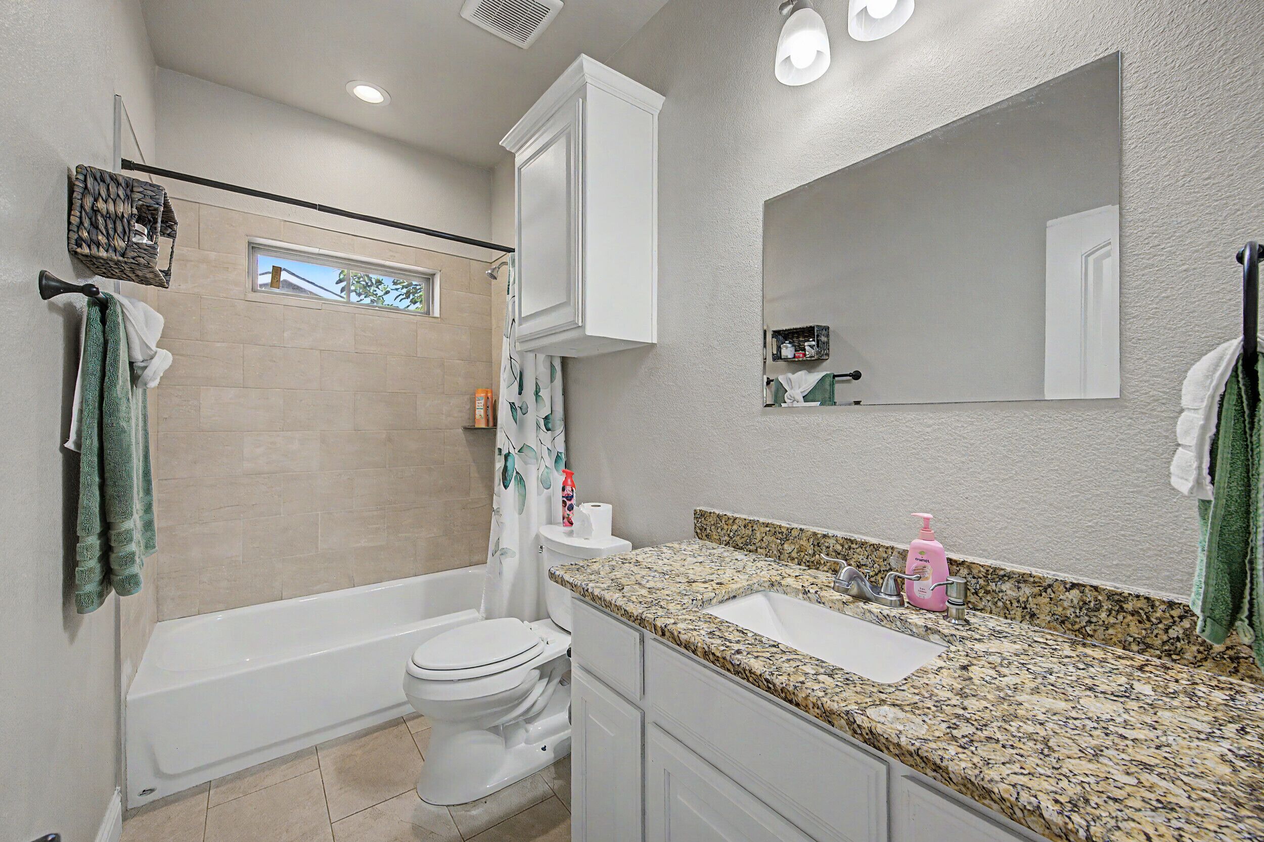 A bathroom with a bathtub, toilet, sink, and a large mirror.