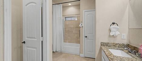 Un baño con encimera de granito, lavabo, ducha e inodoro.