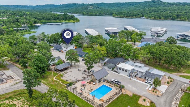 Vista aérea de una propiedad junto al lago con piscina, varias construcciones y embarcaciones amarradas.