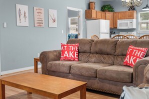 Ein Wohnzimmer mit einem braunen Sofa, zwei roten Kissen, einem Holztisch und Wandbildern mit Fischen.