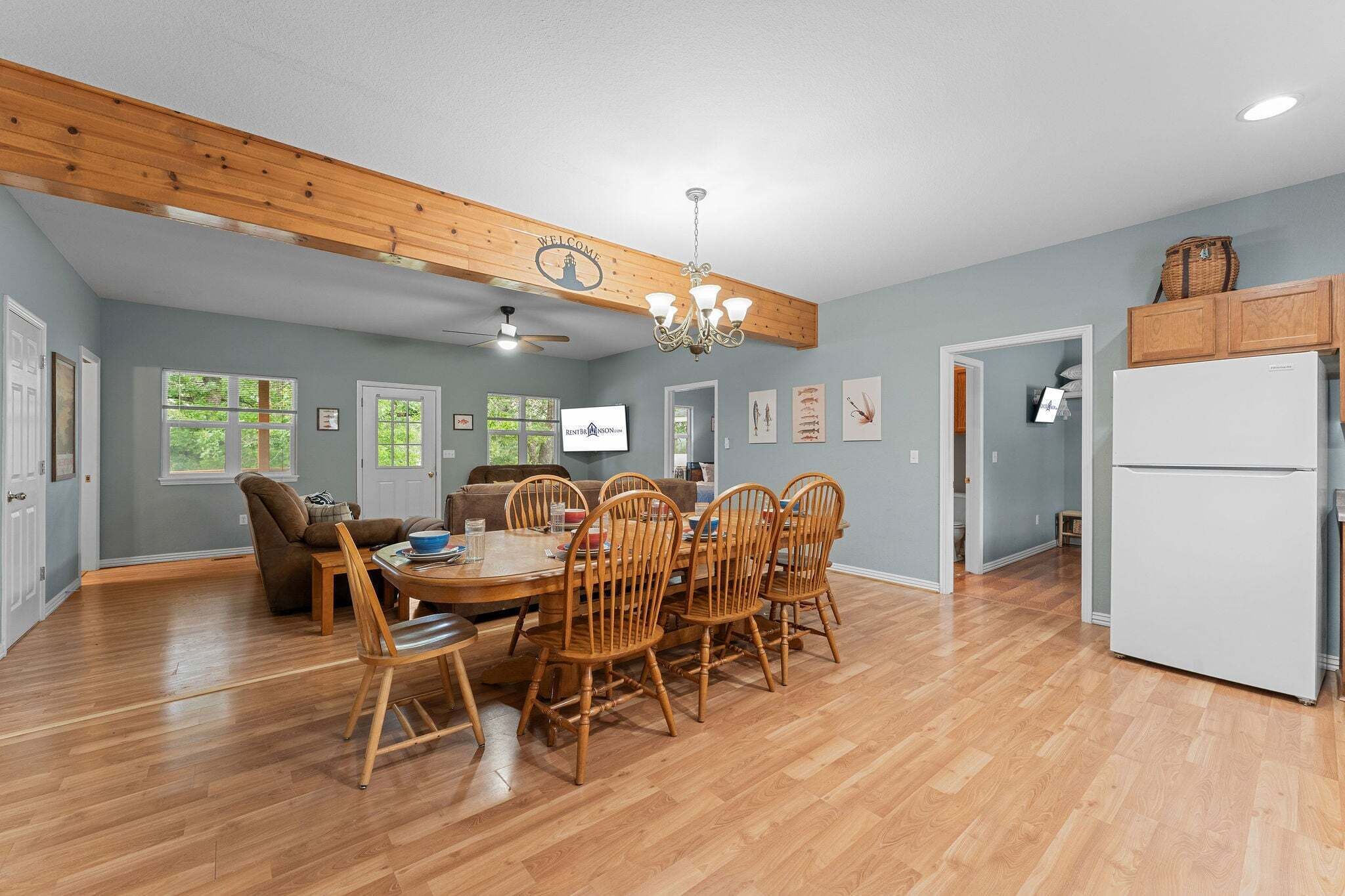 A spacious kitchen with wooden cabinets, a dining area with a wooden table and chairs, and a ceiling fan.