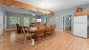Una cocina amplia con armarios de madera, un comedor con mesa y sillas de madera, y un ventilador de techo.