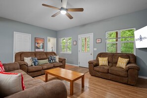 A living room with two brown sofas, a wooden coffee table, and a ceiling fan. - Steps to Table Rock Lake & Port of Kimberling_Free Attraction Tickets (Kimberling City)