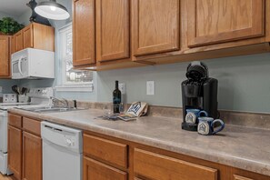 Eine Küche mit Holzausstattung, einer Mikrowelle, einer Kaffeemaschine und einem Geschirrspüler.