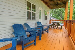 Eine überdachte Veranda mit Holzboden, blauen Adirondack-Stühlen und einem Picknicktisch.
