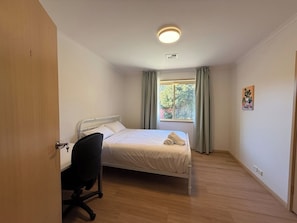 A bedroom with a bed, a desk, and a window with curtains. - Inner North Gem | King Room Near ANU and City Centre (Turner)