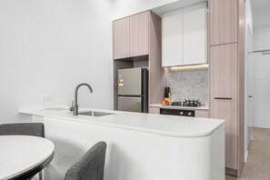 Eine moderne Küche mit Kochinsel, integrierten Geräten und einem Essbereich mit Tisch und Stühlen.