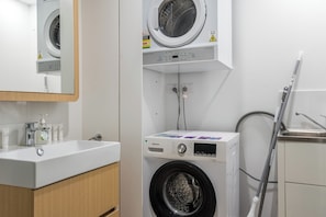 Een wasruimte met een wasmachine, een droger en een wastafel met toiletartikelen.
