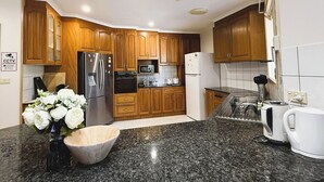 A modern kitchen with wooden cabinets, stainless steel appliances, granite countertops, and a built-in microwave.
