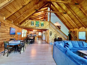 Ein geräumiges Blockhaus-Interieur mit Essbereich, Küche und einem blauen Sofa.