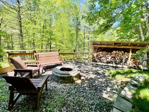 Eine Holzterrasse mit einer Bank und einem Feuerkorb, umgeben von Kies.