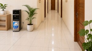 Un couloir d’hôtel avec un distributeur d’eau, des plantes en pot et une porte portant le numéro 106.