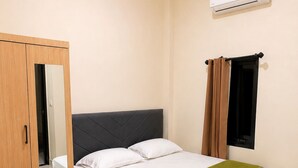 Une chambre à coucher comprenant un lit, une armoire, une fenêtre avec des rideaux et un appareil de climatisation.
